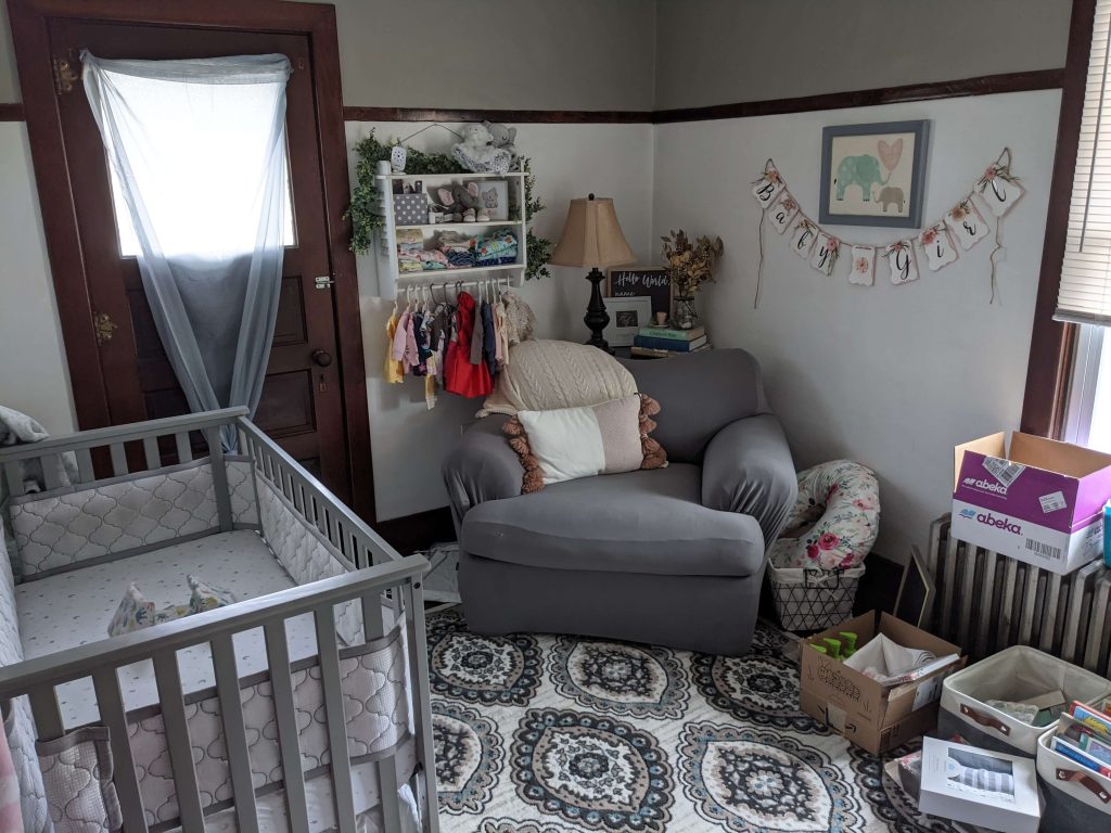 a baby's room with a grey and white crib and large grey chair and baby wall art
